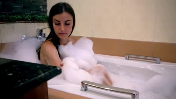a lány abban rejlik, hogy a fürdőszoba, és a fehér hab ellazítja. 4k - Felvétel, videó