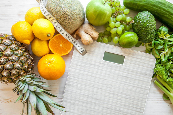 Flat lay composition with scales, healthy vegetables and fruit on wooden background. Weight loss diet - Photo, Image