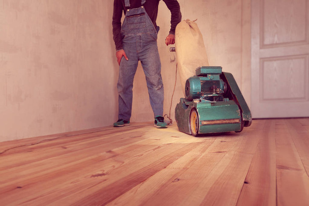 carpenter works by electric grinding wood machine in a room - Photo, Image