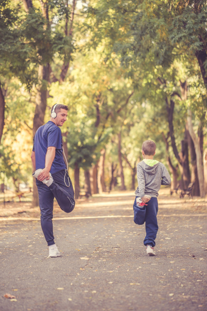 Little boy and his father exercising together in the park - Foto, Imagen