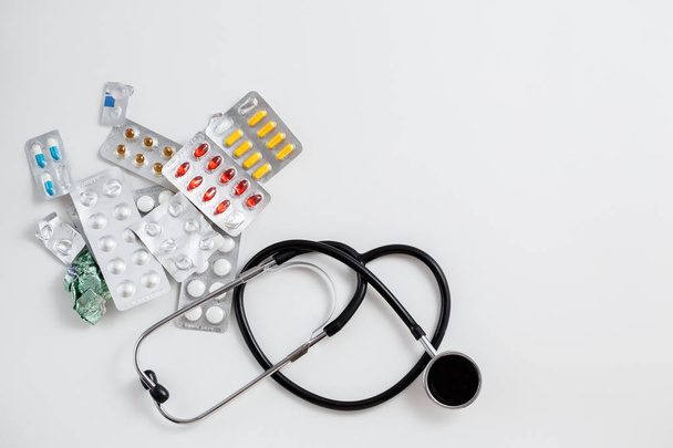 Концепция медицины. Различные препараты и стетоскоп на белом изолированном фоне. Вид сверху
 - Фото, изображение