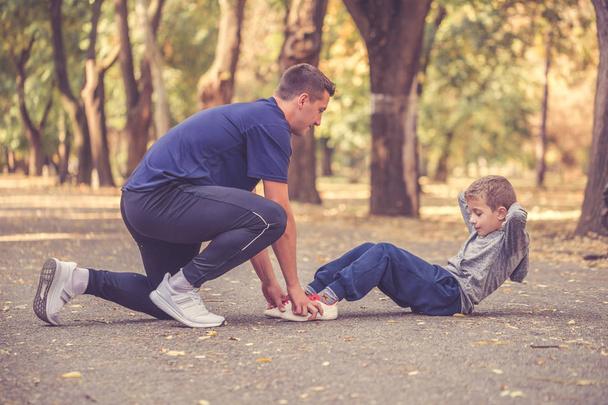 Piccolo ragazzo e suo padre che esercitano insieme all'aperto
 - Foto, immagini