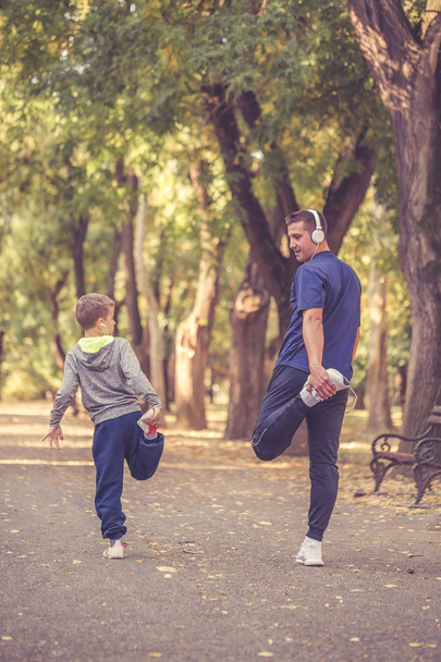 少年と彼の父親、公園で一緒にストレッチ脚 - 写真・画像