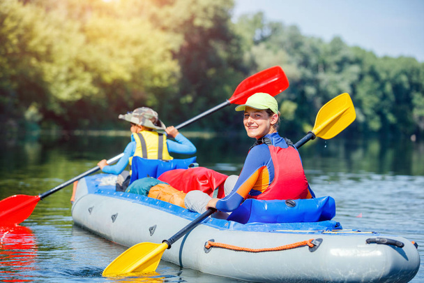 Happy kids kayaking on the river on a sunny day during summer vacation - Foto, Imagem