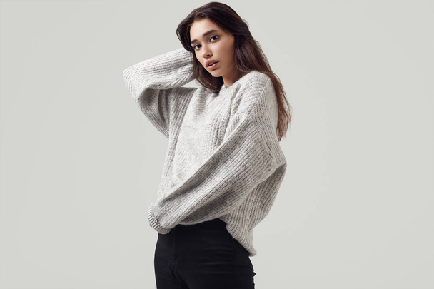 Beautiful brunette woman in sweater posing in studio - Photo, Image