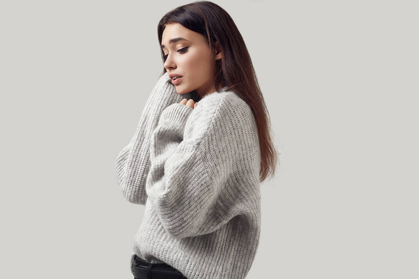 Όμορφη μελαχρινή γυναίκα σε πουλόβερ ποζάρει στο studio - Φωτογραφία, εικόνα