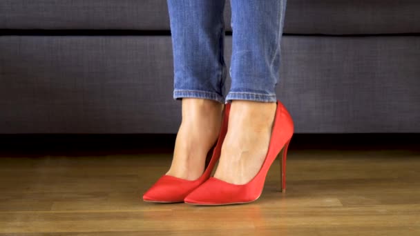 Γυναίκα στον καναπέ σε κόκκινο ψηλά τακούνια δείχνει και διασχίζει σέξι και Slim μακριά πόδια - Πλάνα, βίντεο