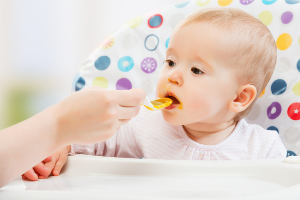 Mamá alimenta divertido bebé de cuchara
 - Foto, imagen