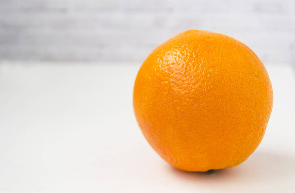 One orange on a white background. There is a place for text. - Foto, afbeelding