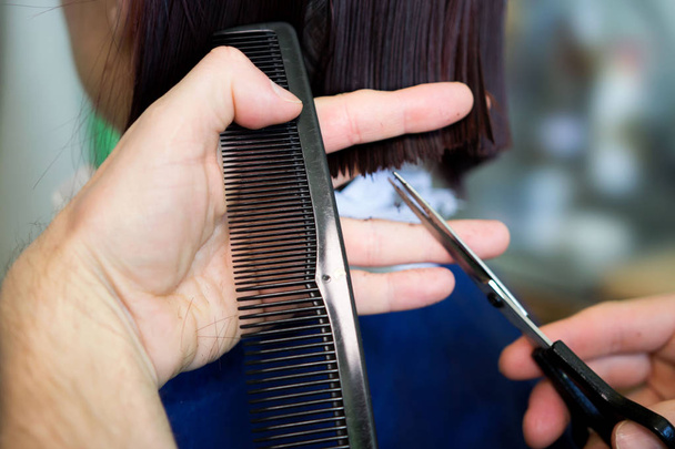 Rossa giovane donna ottenere taglio di capelli da parrucchiere uomo, che fa un taglio di capelli bob prima di tingere
. - Foto, immagini