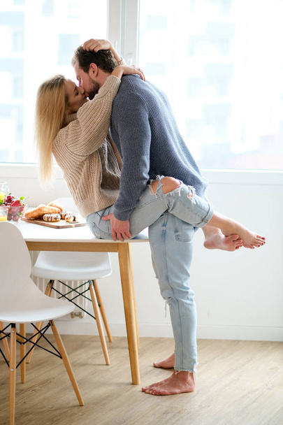 Happy young couple spending nice time together, hugging and kisses each other. At home - Foto, Imagen