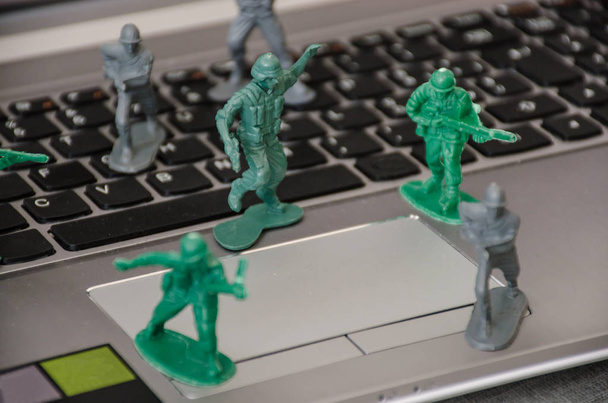 Zabawkowe żołnierzyki umieszczony na klawiaturze notebooka do obrony przed atakiem wirusów komputerowych. - Zdjęcie, obraz