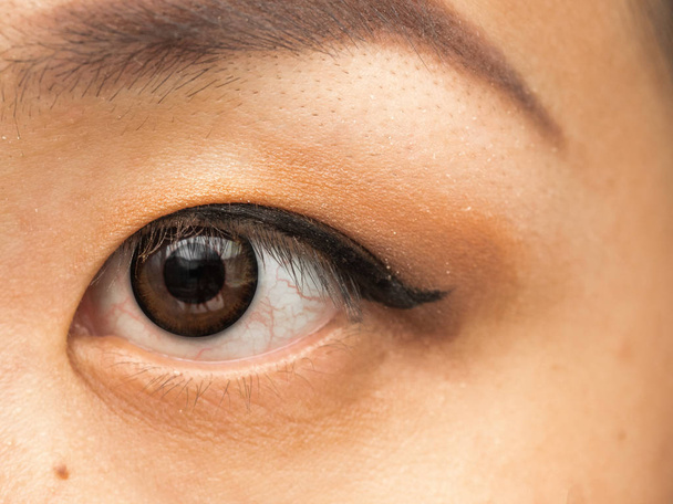 Emberi ázsiai nő nő szeme közeli részlet, smink, a black szemhéjtus és a piros véna. a szeme bevérzett, alvás, vírusos fertőzés vagy irritáció hiánya. Vörös erek. - Fotó, kép