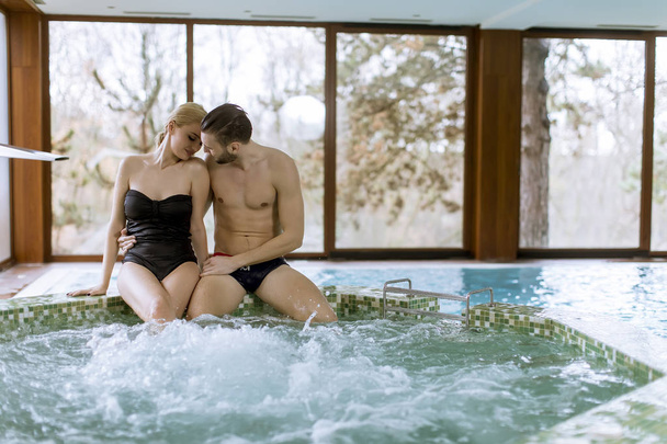 Amar pareja joven relajarse en el centro de spa junto a la piscina
 - Foto, imagen