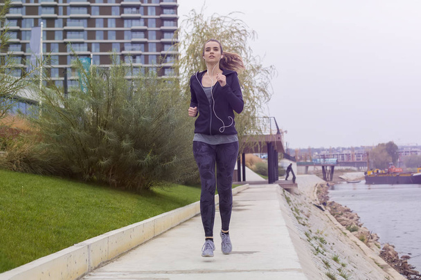 Active young beautiful woman running in urban enviroment - 写真・画像
