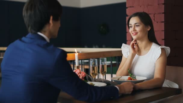 Beautiful young lady is happy and surprised after getting marriage proposal from her boyfriend on date in restaurant. She is taking ring, laughing and speaking. - Materiał filmowy, wideo