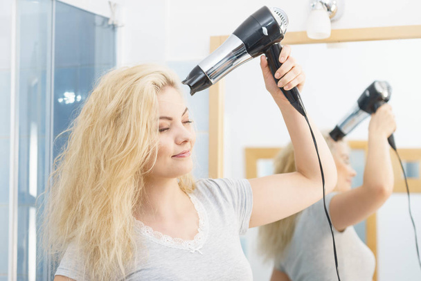 Blonde woman using hair dryer - Zdjęcie, obraz