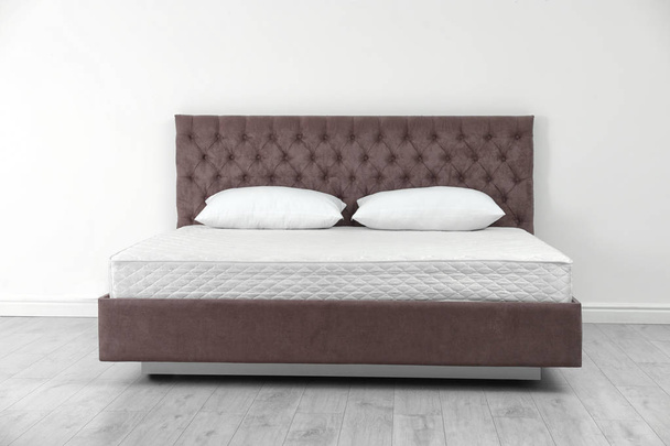 Comfortable bed with new mattress near wall in room. Healthy sleep - Fotó, kép