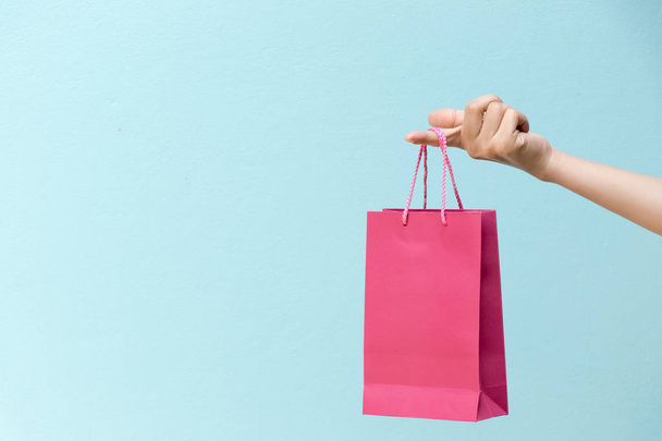 ビジネスの女性の手は青いコンクリート b のピンクのショッピング バッグを保持します。 - 写真・画像