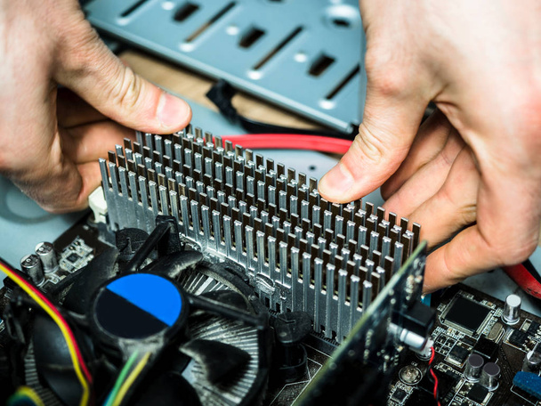 Man's hand installing random access memory ram with radiator in the motherboard slot, socket PC computer assembling. - Photo, Image