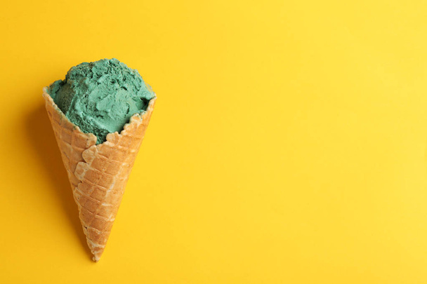 Delicious spirulina ice cream cone on color background, top view. Space for text - Фото, изображение