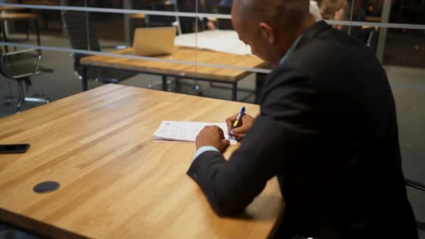 Africký podnikatel a jeho bělošský kolega podepisují pracovní dokumenty v průběhu schůze - Záběry, video