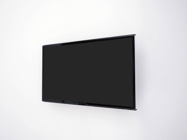 Tela plana preta 4K LED TV moderna pendurada em uma parede branca, Mockup para design
 - Foto, Imagem