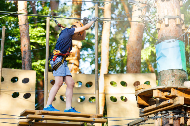 Lindo niño en casco con equipo de escalada en el parque de atracciones de cuerda. Campamento de verano, concepto de vacaciones. Estilo de vida activo
  - Foto, imagen