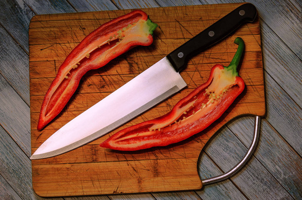Légumes pour un végétarien - poivrons rouges doux coupés en fines tranches à côté d'un couteau tranchant sur une planche à découper. Alimentation saine, isolée. Gros plan
. - Photo, image