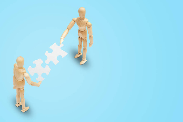 Business Teamwork Concept: Due manichini in legno che tengono insieme e collegano pezzi di puzzle in carta bianca
. - Foto, immagini
