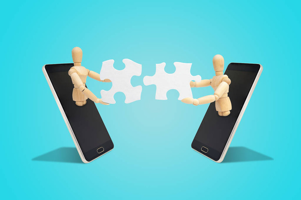 Business Communication and Teamwork Concept : Two wooden figure mannequin holding and connecting white paper puzzle piece together. - Photo, Image