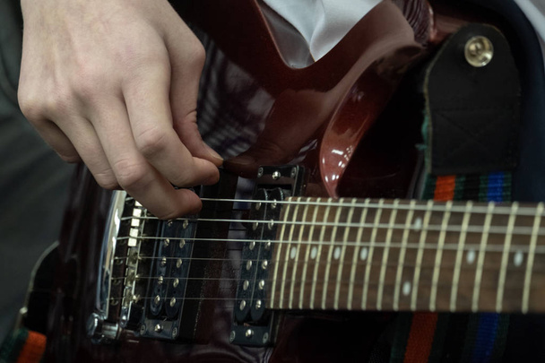 ティーンエイ ジャーは、エレク トリック ギターを果たしています。若いベーシストの指は、低音弦を引いています。音楽のテーマ。クローズ アップ. - 写真・画像