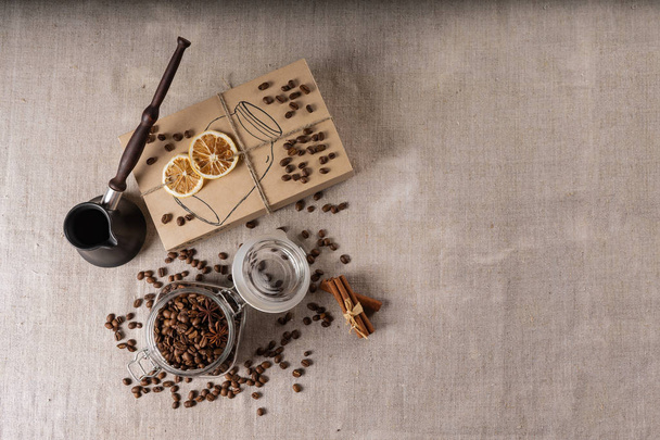 Cezve and roasted coffee beans in box on a rustic table, cinnamon and dried lemon. - Photo, image