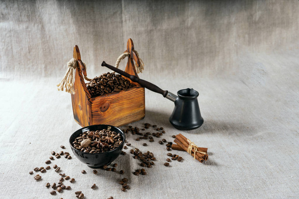 Cezve and roasted coffee beans in box on a rustic table, cinnamon and dried lemon. - Фото, зображення