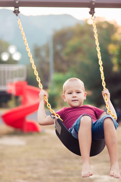 Little boy swinging on a swing - Fotó, kép