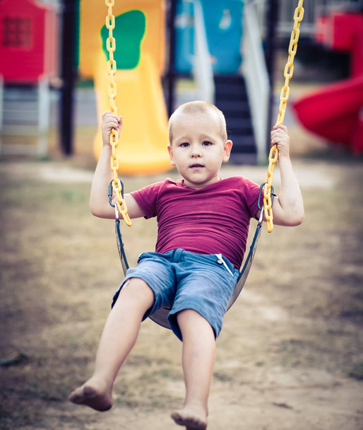 Little boy swinging on a swing - Fotoğraf, Görsel