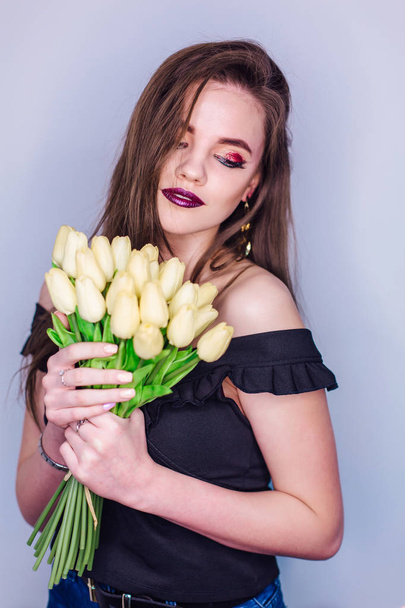 Beauty portrait of a woman with bright colorful make-up and bouquet of yellow tulips - Foto, Imagen