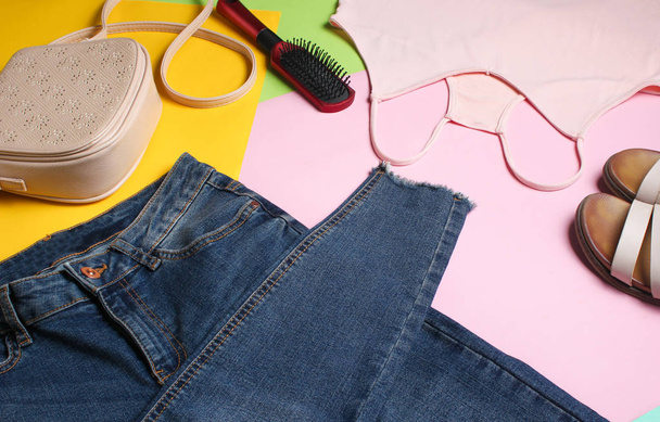 Accesorios y ropa de mujer sobre un fondo pastel de colores. Jeans, sandalias, camiseta, bolso, peine
. - Foto, imagen
