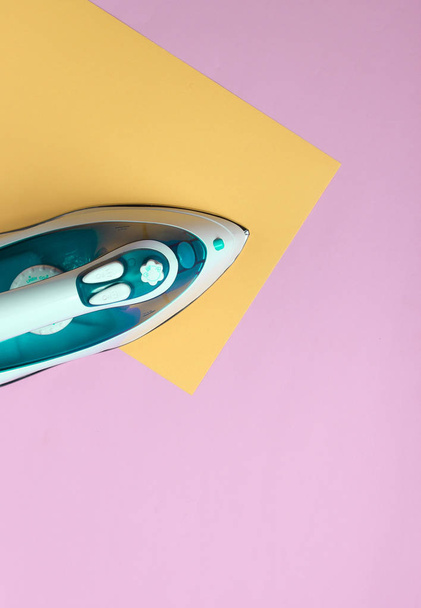 Iron for ironing on a colored pastel background, top view. Minimalis - Фото, изображение