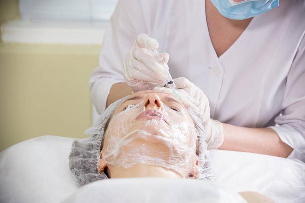 Cosmetologue travaillant avec les clients face. Procédure cosmétique de mésothérapie. Faire des injections dans un front
 - Photo, image