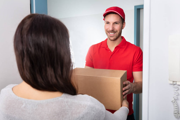 Close-up Of Woman Taking Cardboard Box From Delivery Man - Fotoğraf, Görsel