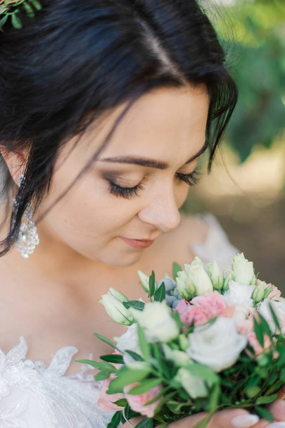 Very beautiful bride is holding a bouquet. - Photo, image
