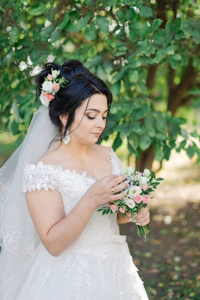 Very beautiful bride is holding a bouquet. - Foto, afbeelding