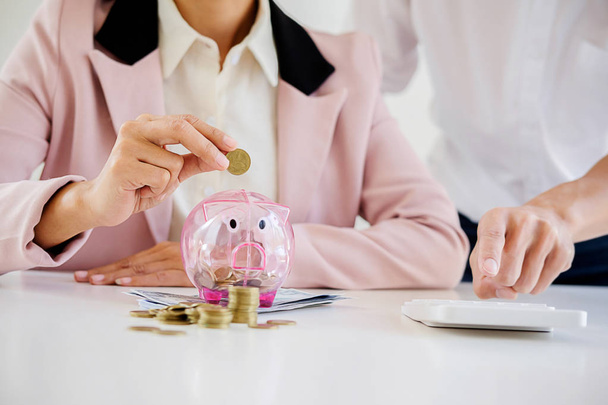Business people sheltering coins and piggy bank at desk. saving concept - Photo, Image