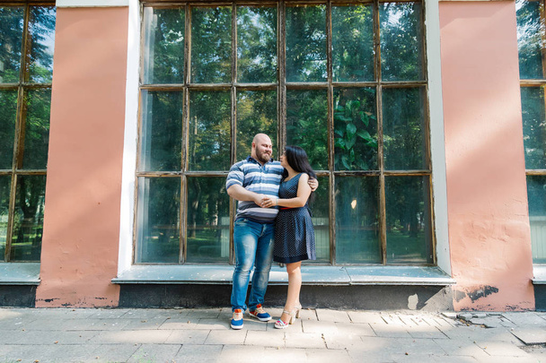 Δύο ερωτευμένα σταθεί αγκάλιασμα από μεγάλα παράθυρα στο πάρκο και να φαίνονται σε κάθε άλλο. - Φωτογραφία, εικόνα