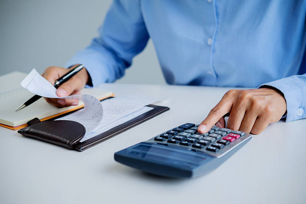 Nő a számlát, a számológép. Nő kalkulátor segítségével számítja ki a számlákat az asztalnál, az office. A költségek kiszámítása. - Fotó, kép