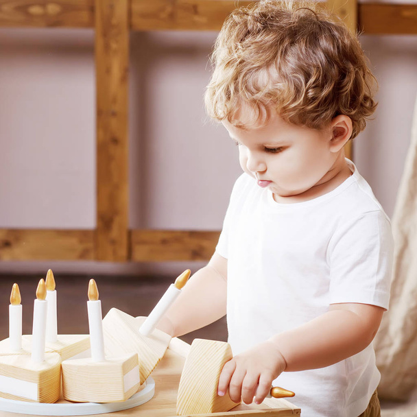 Child boy playing in his room with a wooden toy cake - 写真・画像