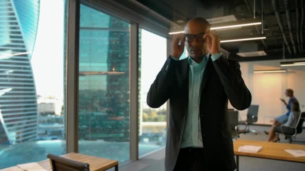 Νέος Αφρικανός Αμερικανός αρσενικός επιχειρηματίας βάζοντας τα γυαλιά και κοιτάζοντας την κάμερα - Πλάνα, βίντεο