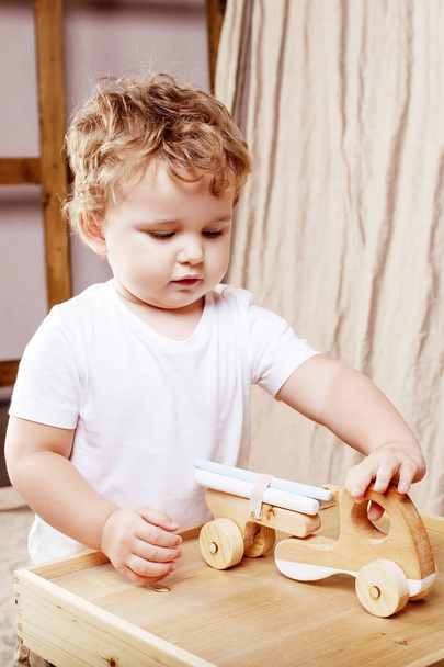 Child boy playing in his room with a wooden toy car - Фото, зображення