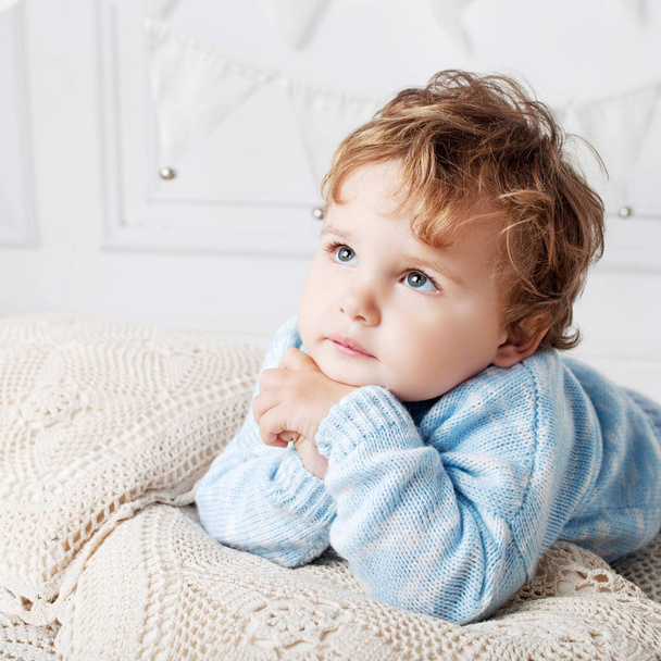 Portrait of happy adorable baby boy on the bed in his room. Thou - 写真・画像